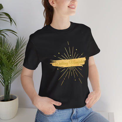 Woman wearing a Classic black "Walking Manifestation" T-shirt featuring a gold fireworks design. Perfect for motivation, self-empowerment, and stylish everyday wear. Sizes: XS, S, M, L, XL, 2XL, 3XL. Luminous Gem Designs.