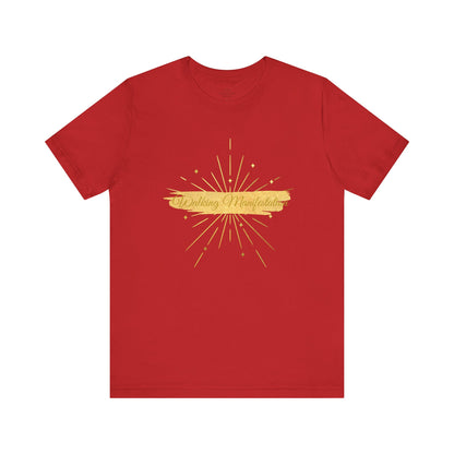 Bold red "Walking Manifestation" T-shirt with an inspiring gold fireworks print. A powerful statement piece for confident individuals embracing success. Sizes: XS, S, M, L, XL, 2XL, 3XL. Luminous Gem Designs.