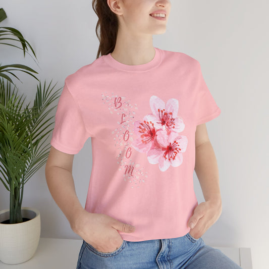 Woman wearing pink "Blossom" T-shirt featuring delicate blooming flowers and petals. A stylish, uplifting piece for casual and semi-formal wear. Sizes: XS, S, M, L, XL, 2XL, 3XL. Luminous Gem Designs