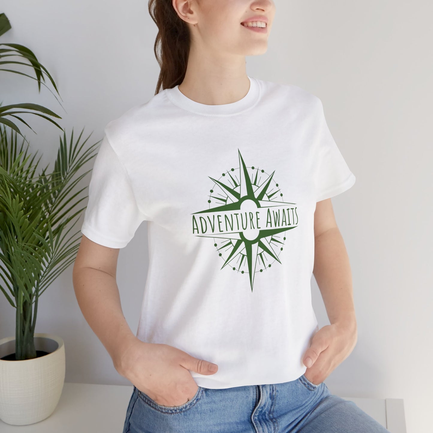 Woman wearing Crisp white "Adventure Awaits" T-shirt featuring an adventure-inspired compass print. A classic, lightweight staple for travelers and explorers. Sizes: XS, S, M, L, XL, 2XL, 3XL. Luminous Gem Designs.