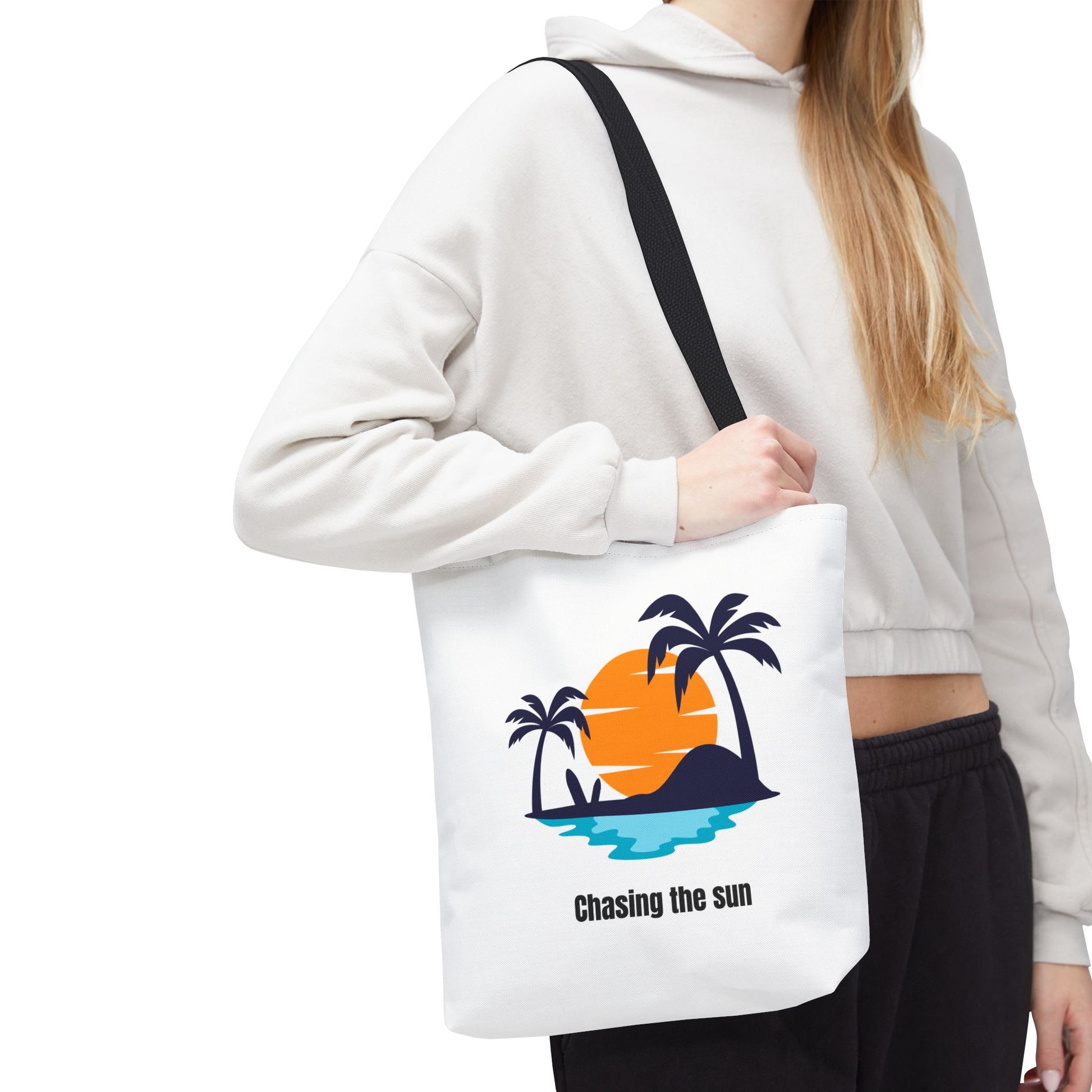 Woman carrying Chasing the Sun tote bag in white with black handles, featuring a tropical palm tree design on her shoulder. This durable 100% polyester tote is perfect for summer adventures, beach trips, or grocery runs. Available in sizes 13"x13", 16"x16", 18"x18". Luminous Gem Designs.