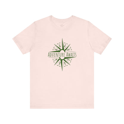 Soft pink "Adventure Awaits" T-shirt with a trendy compass graphic. A comfortable and breathable tee for explorers who love stylish travel gear. Sizes: XS, S, M, L, XL, 2XL, 3XL. Luminous Gem Designs.